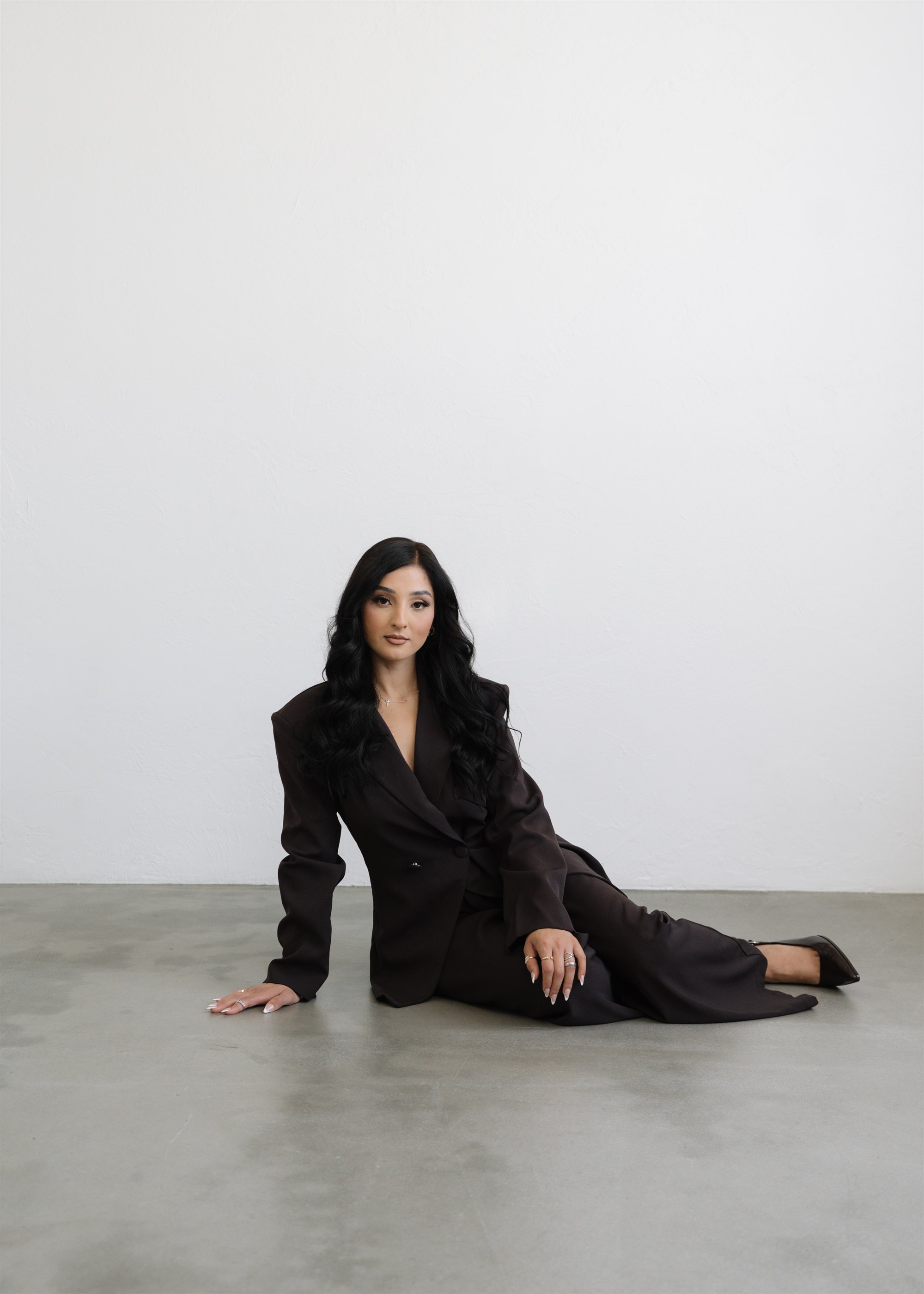 Elizabeth Valdovinos, founder of Texturah, seated on the studio floor in a black suit